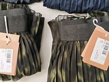 two pairs of skirts with tags on them on a table