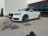une Audi blanche garée devant un immeuble