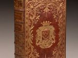 an old book with a gold and red cover on it