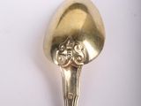 a gold spoon with a face on it on a white surface