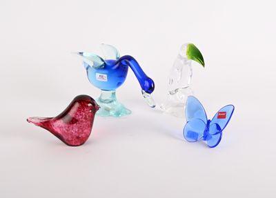 trois oiseaux en verre posés les uns à côté des autres sur une surface blanche
