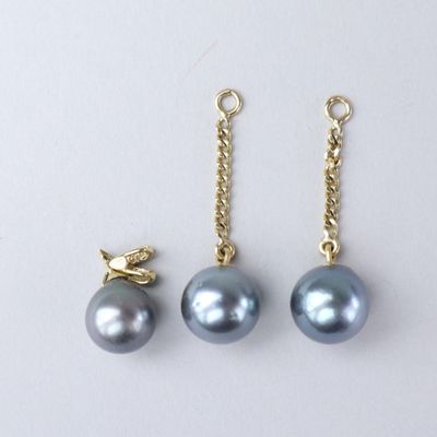 three pairs of grey pearls and a gold chain on a white background