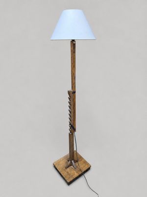 un lampadaire en bois surmonté d'un abat-jour blanc