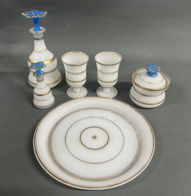 une assiette blanche ornée d'une fleur bleue, à côté d'un service de tasses et de soucoupes