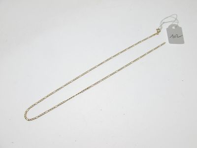 une chaîne en or à laquelle est accrochée une médaille, posée sur une surface blanche