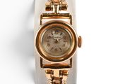 gros plan d'une montre-bracelet en or sur une surface blanche