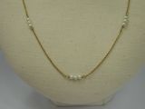 a gold necklace with pearls on a mannequin base