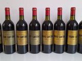 six bottles of red wine lined up in a row on a table