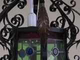 a lamp hanging from the ceiling with a stained glass window