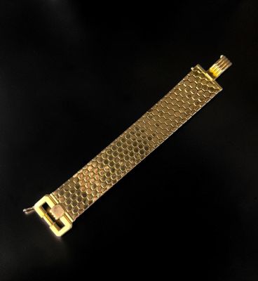 a close up of a gold bracelet on a black background