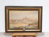 a picture of a painting on a easel with a picture of a town in the background