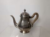 a silver tea pot sitting on a glass table