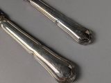 two silverware spoons and a knife on a table