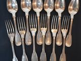 a lot of silver spoons and forks on a table