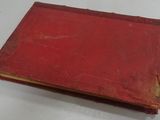 an old red book sitting on top of a white table