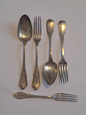 quatre fourchettes, une cuillère et une fourchette posées sur une surface blanche