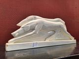 a white sculpture of a running dog on a table