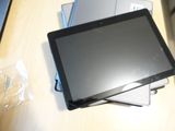 a tablet computer sitting on top of a stack of laptops