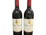 two bottles of red wine sitting next to each other on a white surface