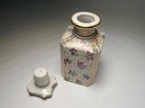 a small vase with a lid sitting next to a smaller one