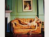 a woman laying on a couch in a green room