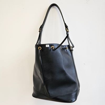 un sac à main en cuir noir accroché à un mur blanc
