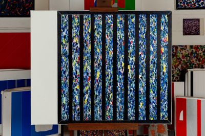 a painting on a easel in a room with many different colored boxes