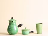 une théière verte et deux tasses placées l'une à côté de l'autre