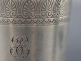 a silver cup that has a monogram on it