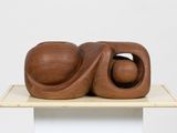 wooden sculpture of two spheres on top of a white pedestal