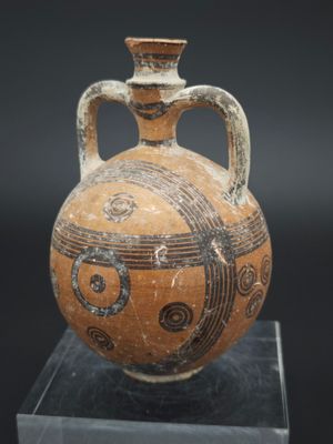 un vase posé sur un socle, sur une surface noire