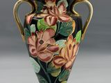 un vase avec des fleurs peintes dessus, posé sur une table