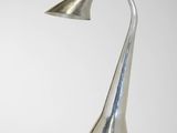 une lampe en métal argenté posée sur une table avec un fond blanc