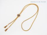 a close up of a gold necklace with a tassel on a white background