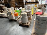 many rolls of paper sitting on pallets in a warehouse