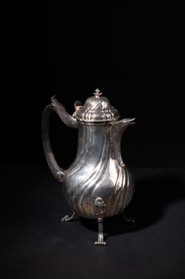 an antique silver coffee pot on a stand against a black background
