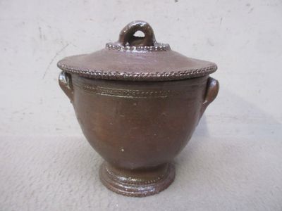 un pot marron avec un couvercle posé sur une surface blanche