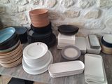 a lot of plates and bowls on a table with a stone wall in the background
