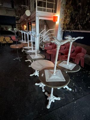 many tables and chairs on the sidewalk outside of a building