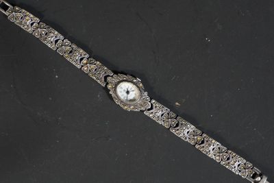 une image représentant une montre-bracelet posée sur une surface noire