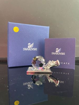 une figurine en cristal posée sur une table, à côté d'une boîte bleue