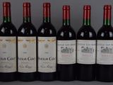 six bottles of red wine lined up in a row on a table