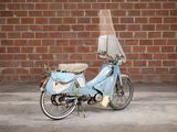 a blue moped parked in front of a brick wall