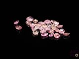 some pink diamonds on a black surface with a black background