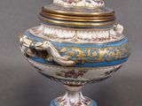 a blue and white vase with a gold lid