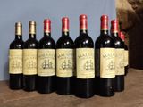 several bottles of wine are lined up on a wooden table