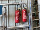 deux extincteurs accrochés au mur à côté d'une échelle