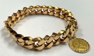 a close up of a gold bracelet with a coin on it