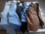 Plusieurs paires de jeans sont empilées sur une palette posée à même le sol