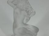 a clear glass statue of a woman holding a flower in her hand